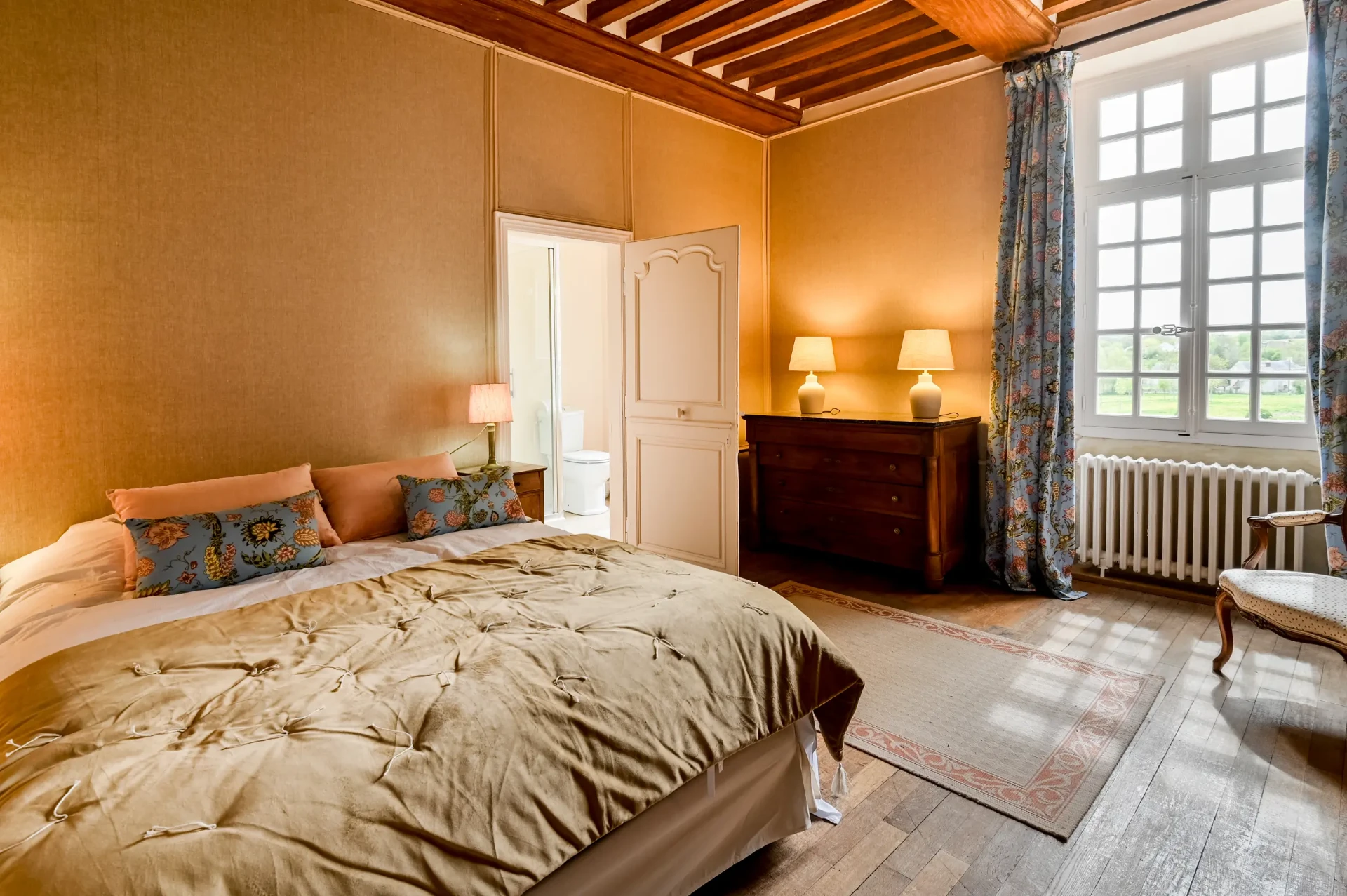 Chambre ocre, poutres et vue sur la campagne